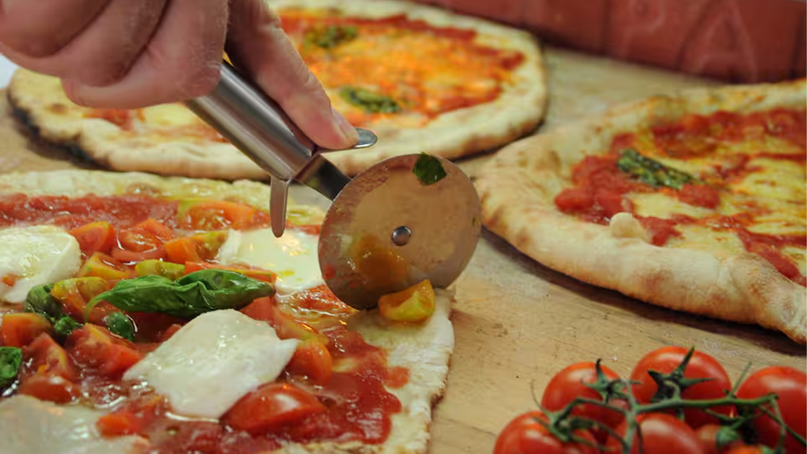 Pizza napoletana appena sfornata che viene tagliata durante la lezione di cucina