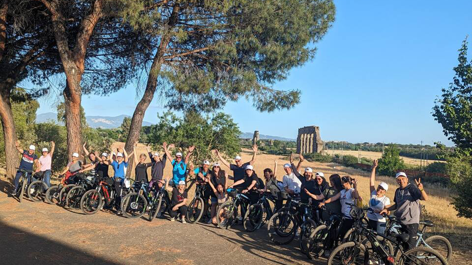 Gruppo di turisti in bicicletta elettrica che pedala sulla Via Appia Antica durante il tour guidato